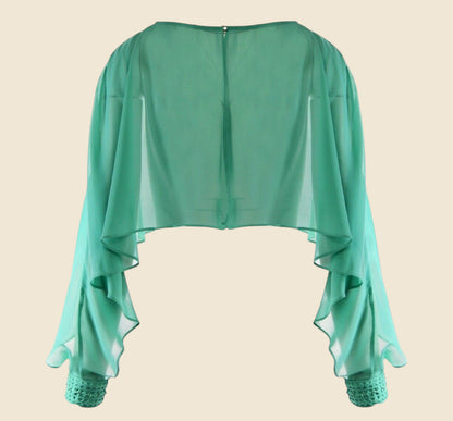 Green sheer top with lace cuffs on a beige background