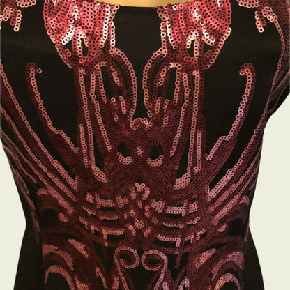 Black top with red sequin pattern on a beige background