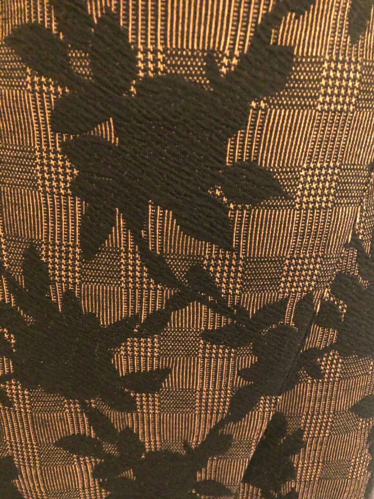 Close-up of a fabric with black floral pattern on a brown checkered background