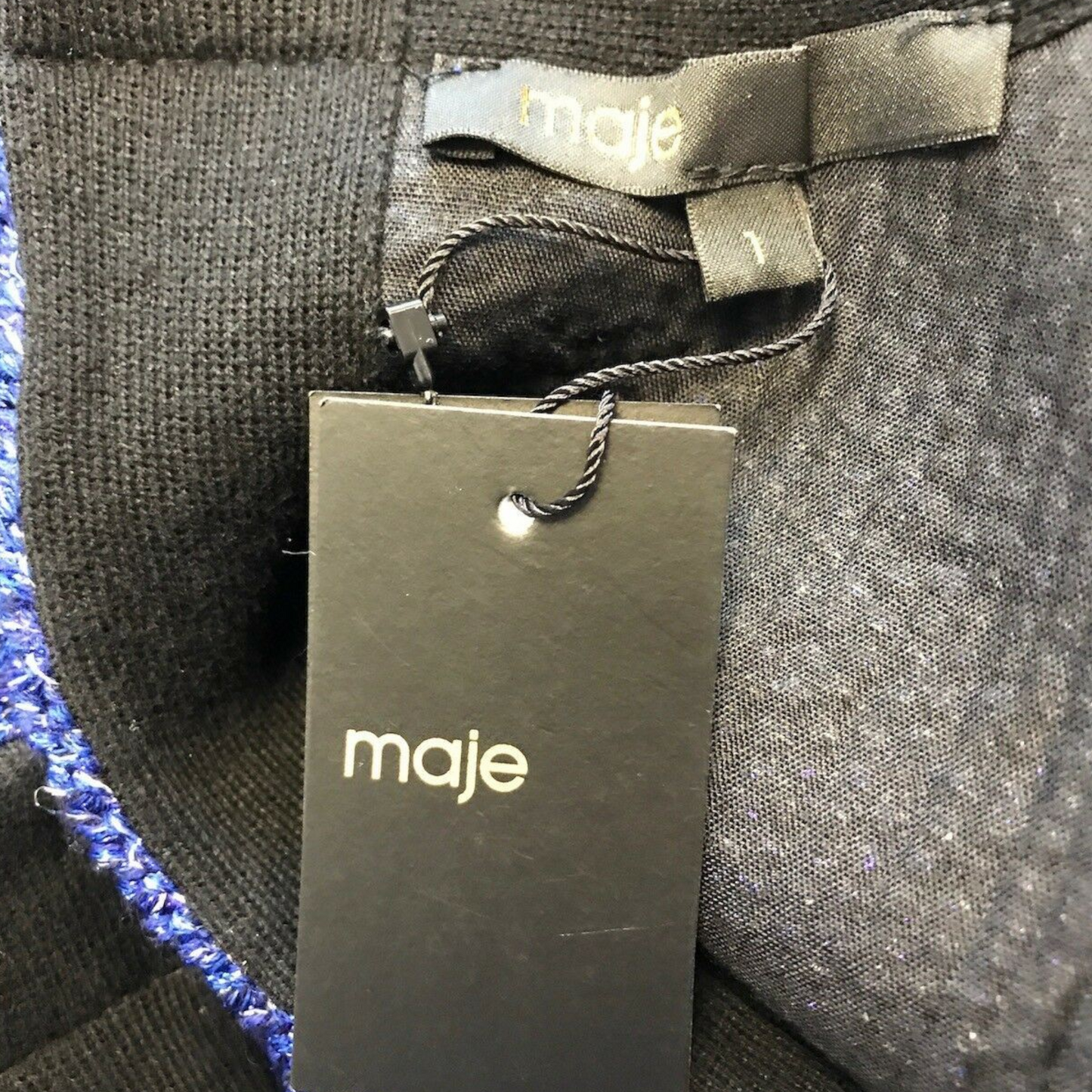 Gray fabric with a Maje tag on a textured surface