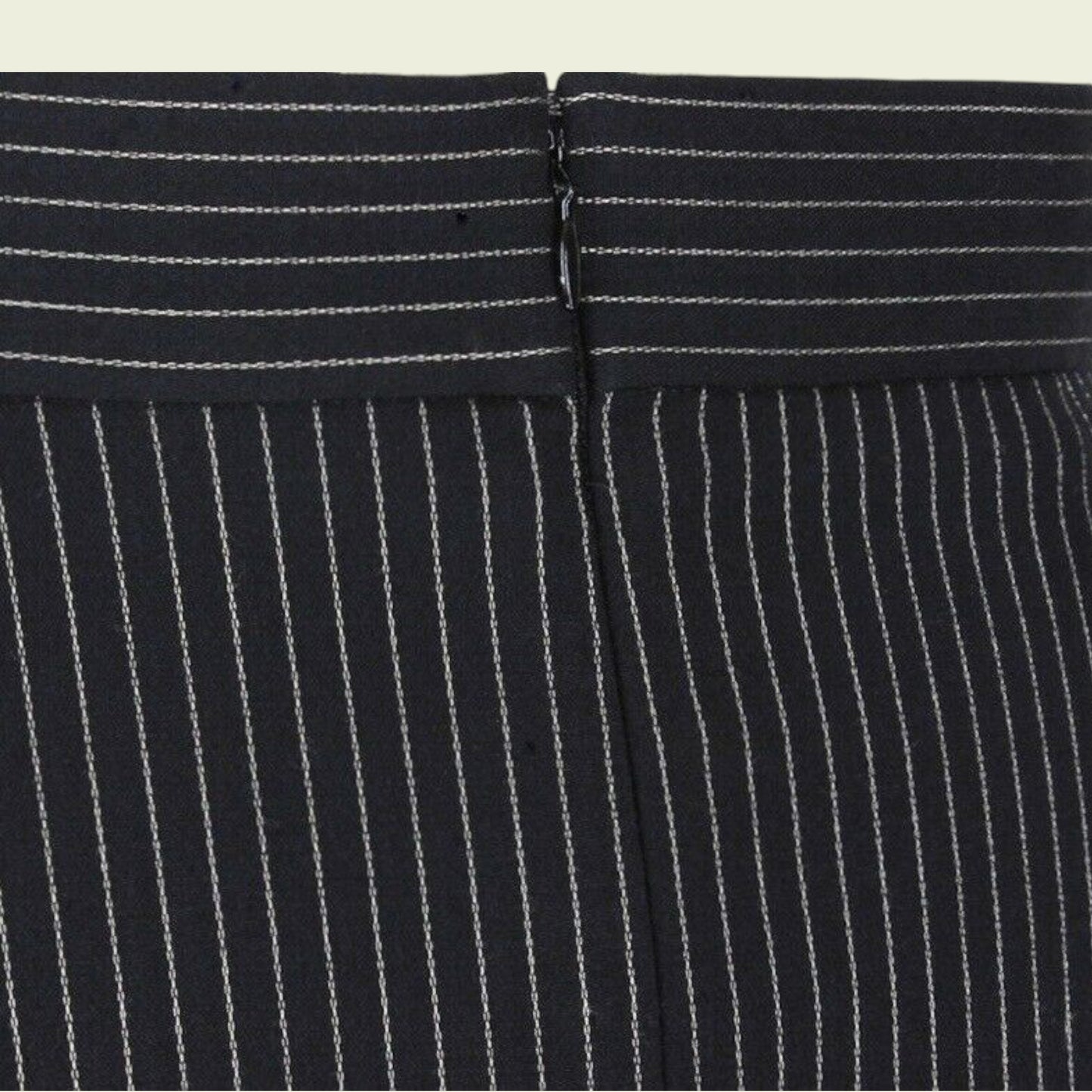 Close-up of a black pinstripe suit with a focus on the waistband.