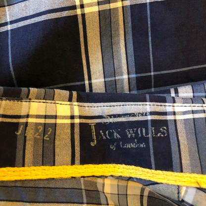 Close-up of a plaid fabric with 'Jack Wills' branding and a yellow waistband.