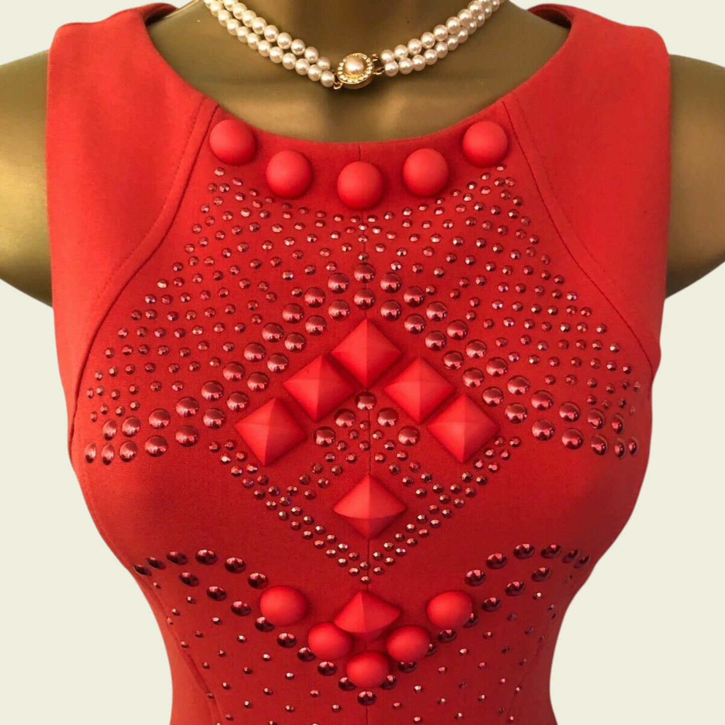 Red dress with diamond pattern and red buttons on a mannequin against a light background