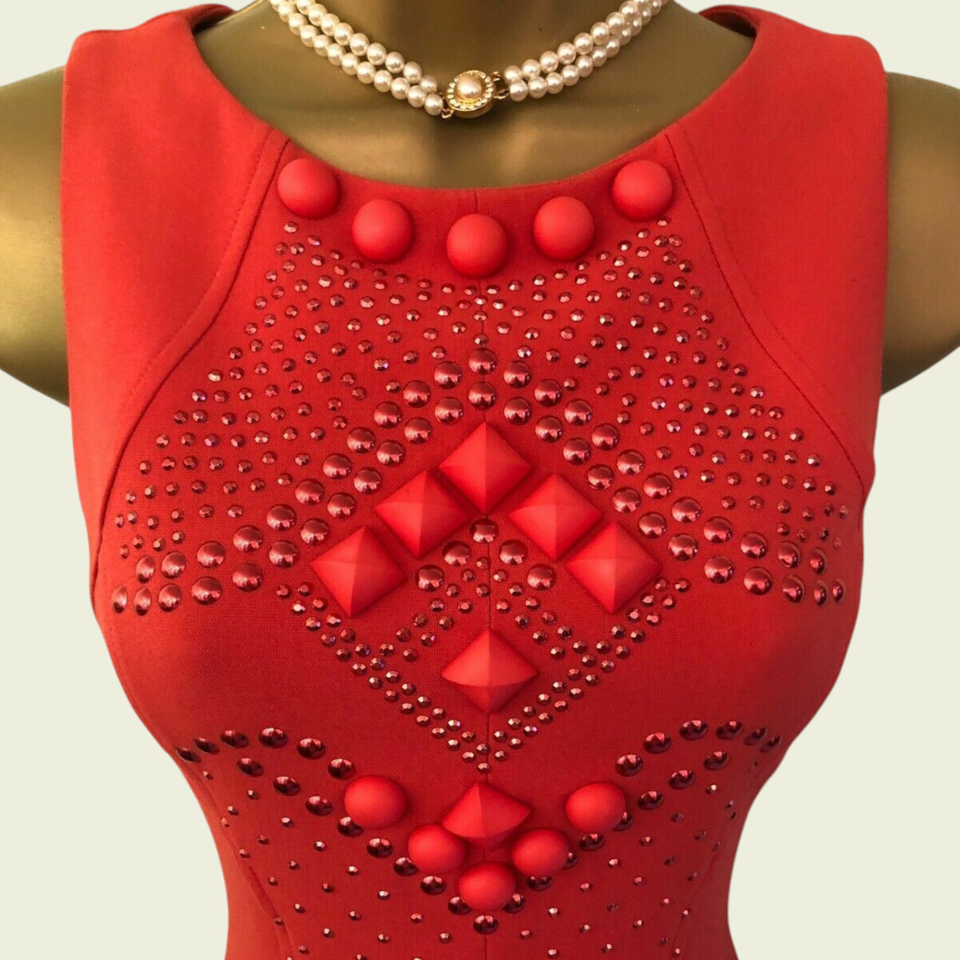Red dress with diamond pattern and red buttons on a mannequin against a light background