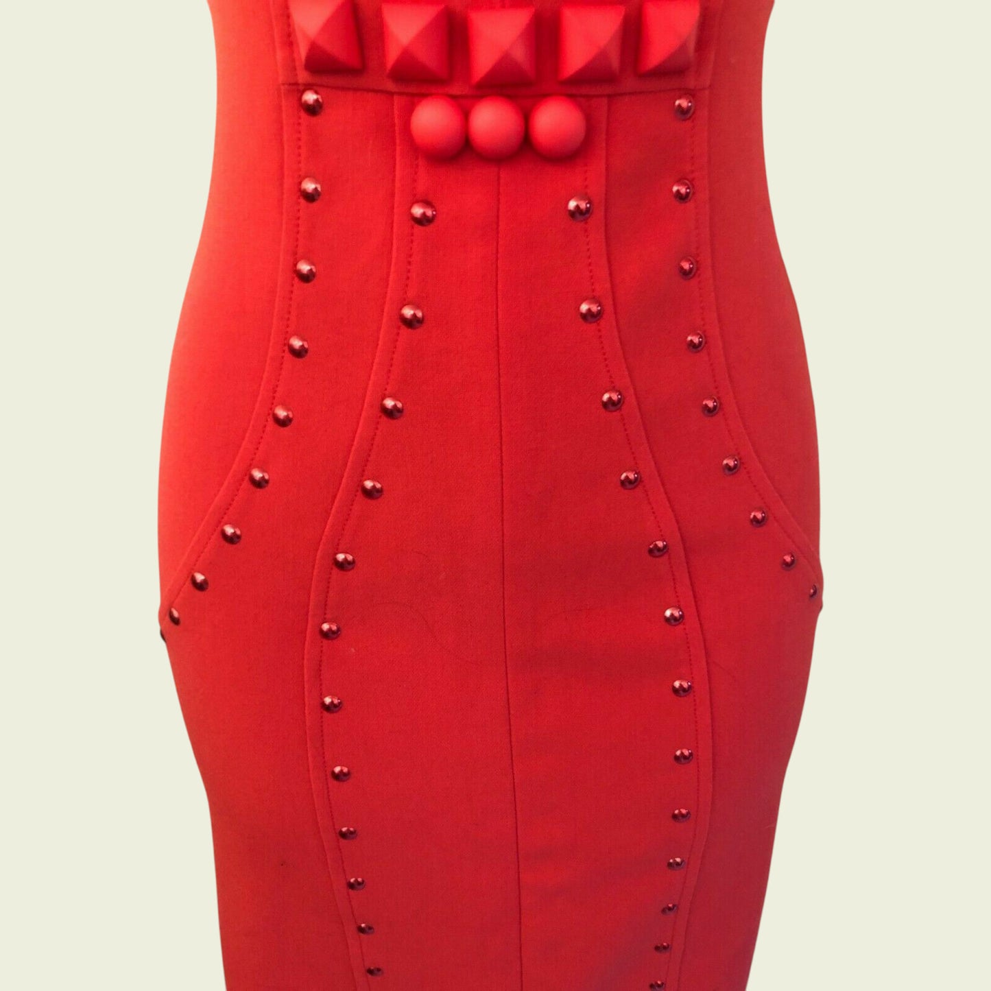 Red dress with studded details on a beige background