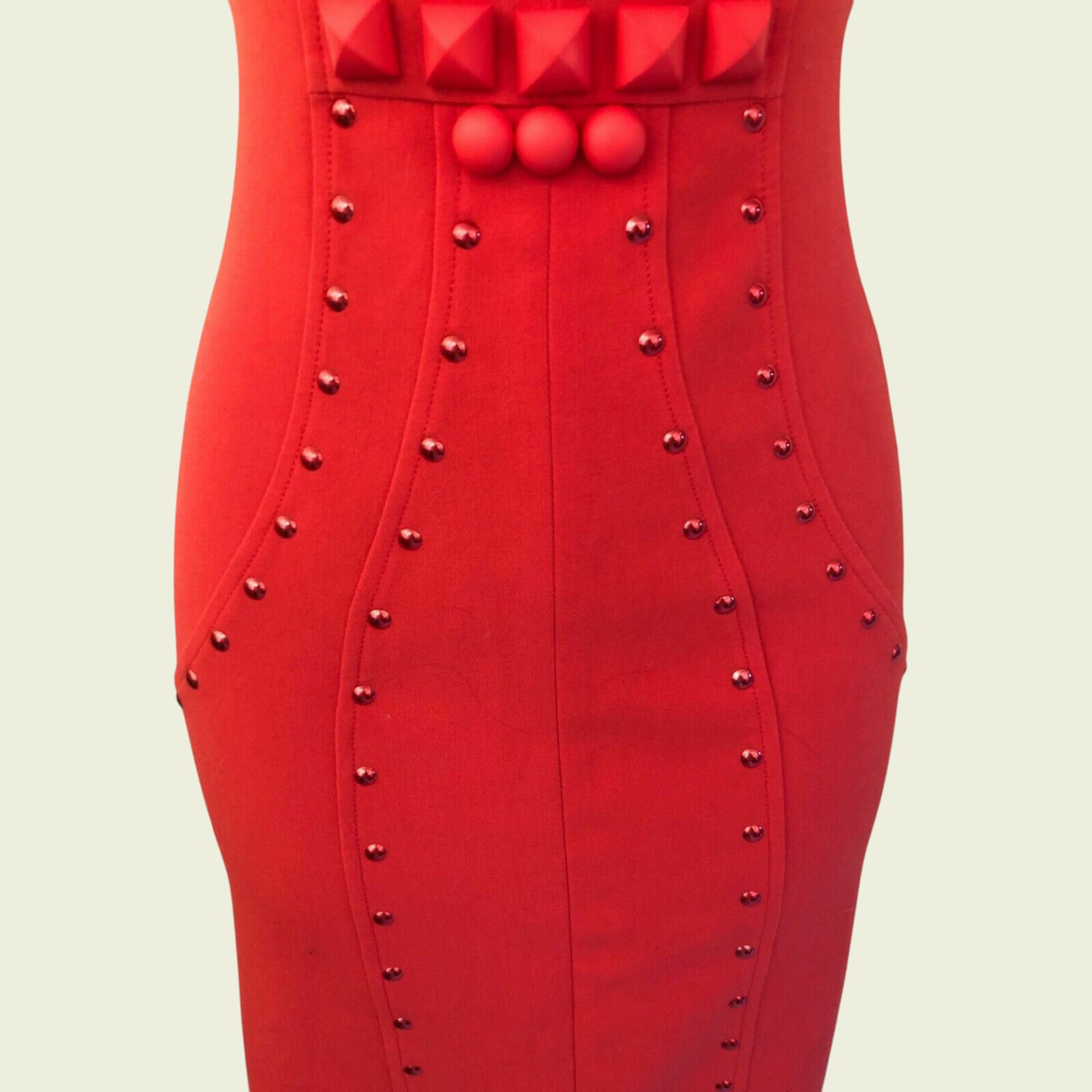Red dress with studded details on a beige background