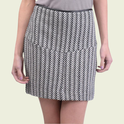 Person wearing a black and white patterned skirt on a beige background