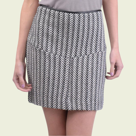 Person wearing a black and white patterned skirt on a beige background