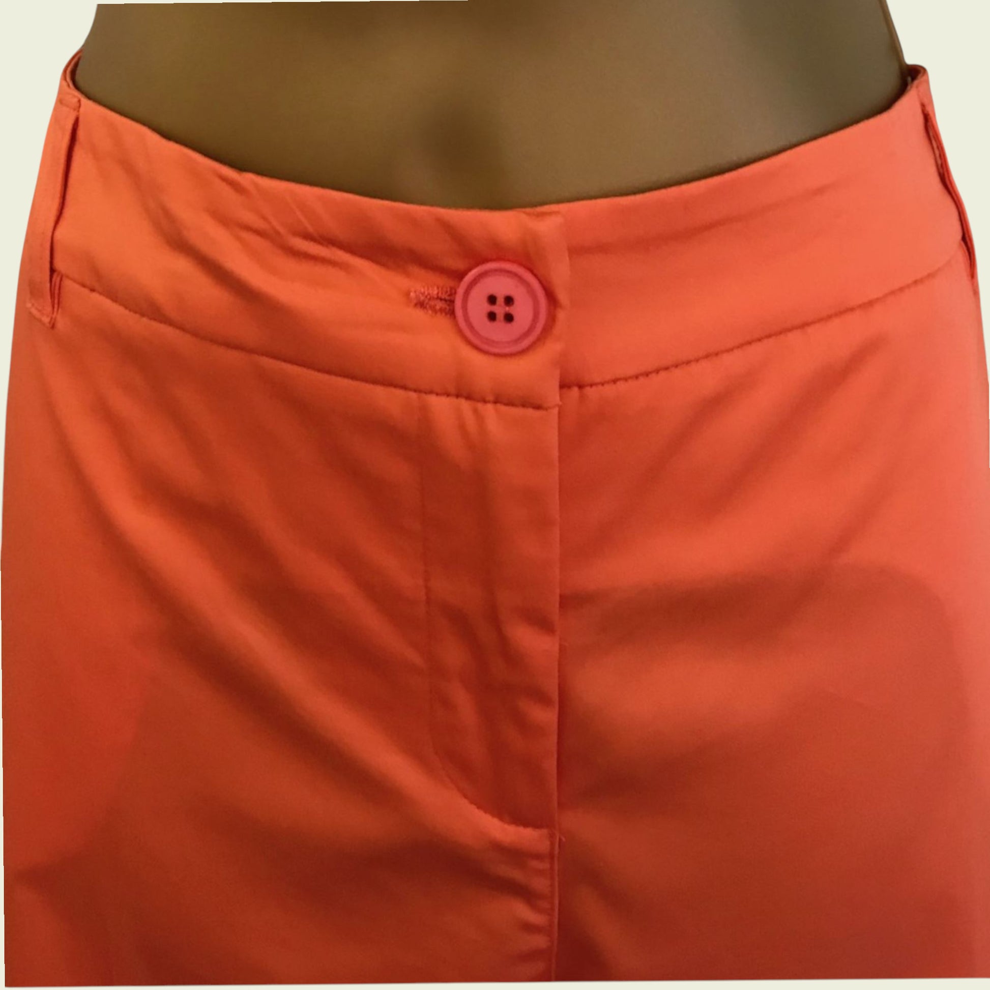 Close-up of orange pants with a button on a beige background