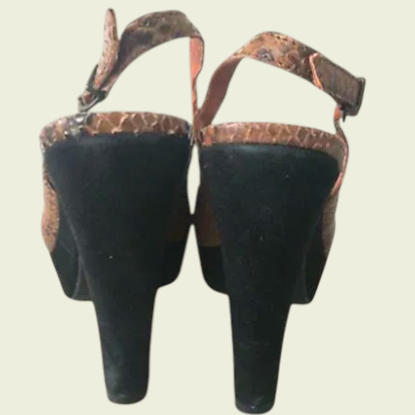 Back of brown open-toe sandals with snake print on a light background