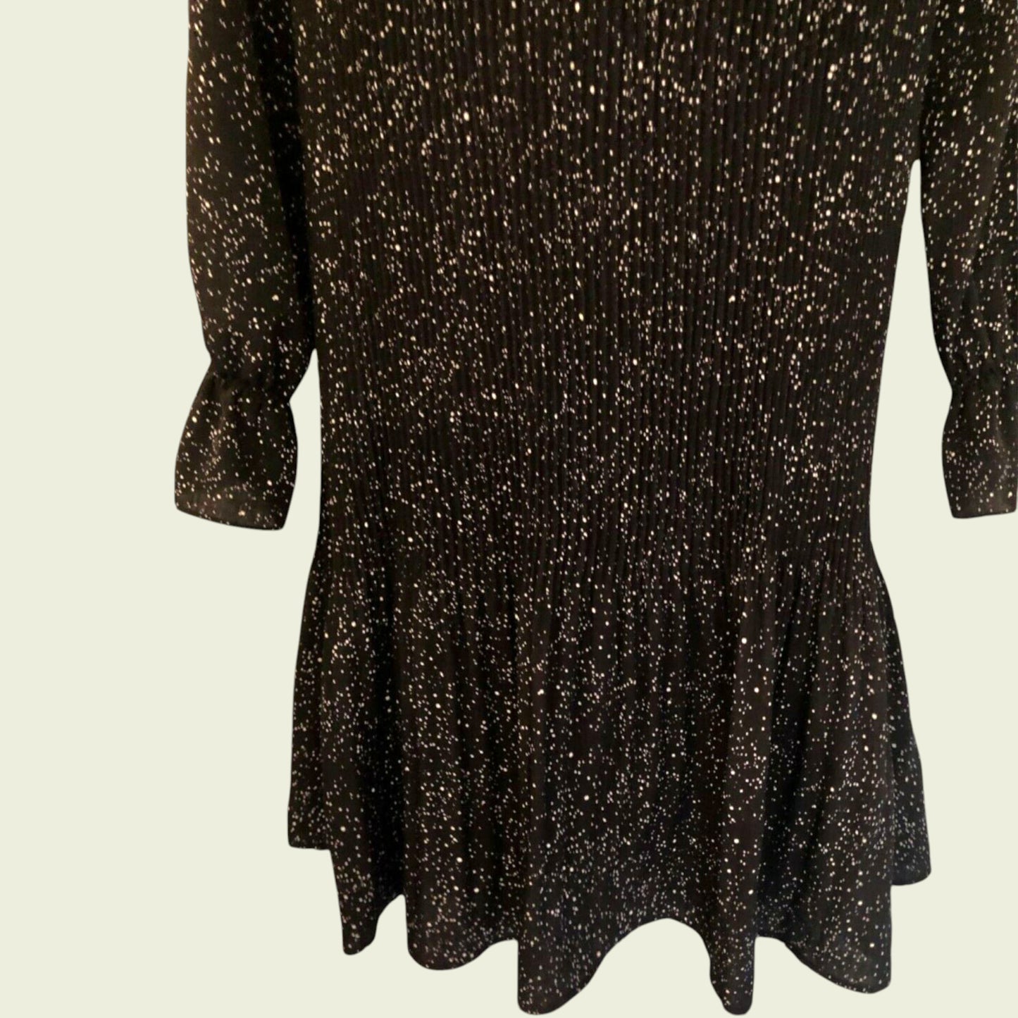 Black and white polka dot pleated dress on beige background