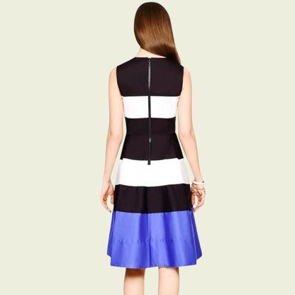 Woman wearing a black, white, and blue dress on a beige background