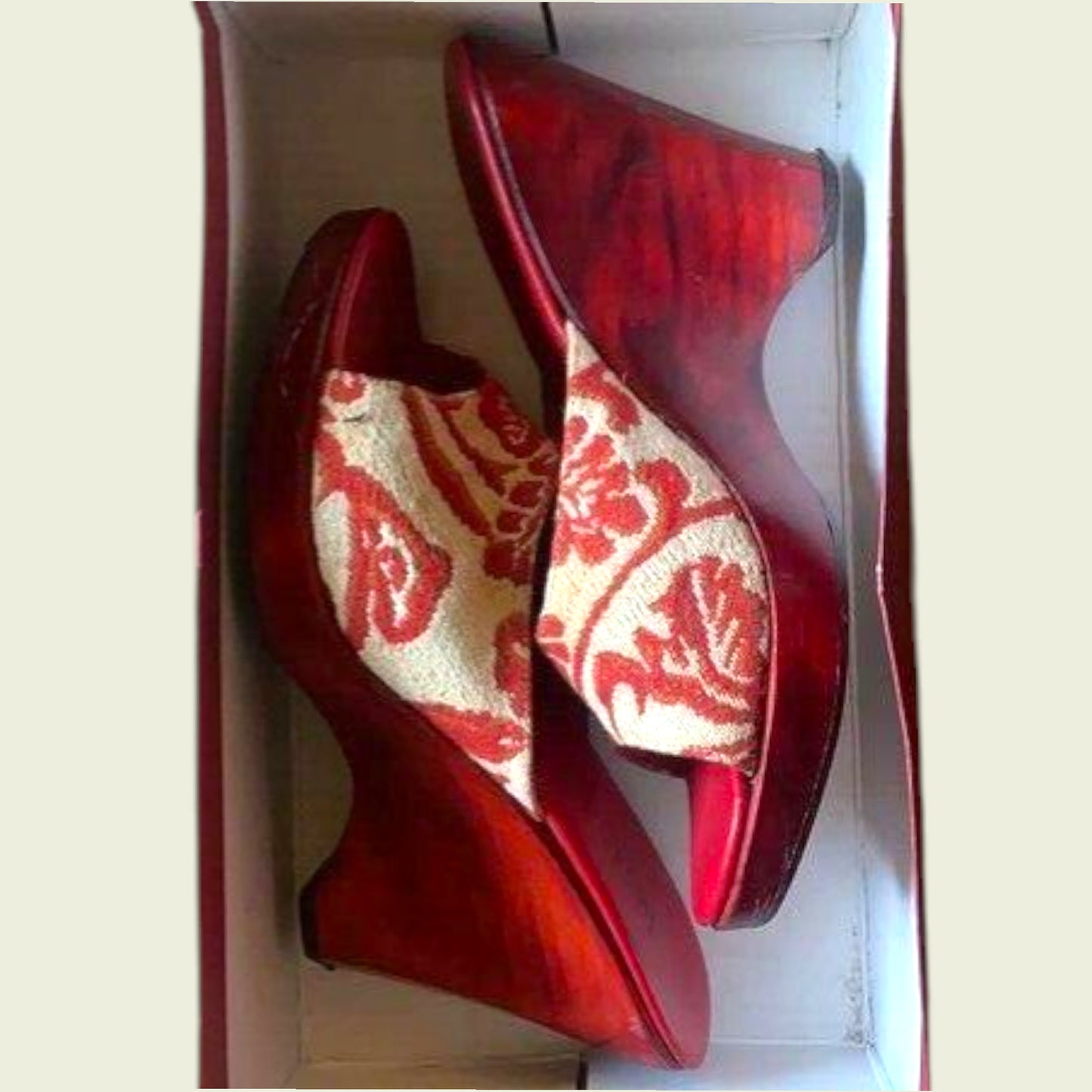 Red and white tapestry high-heeled mules in a box.