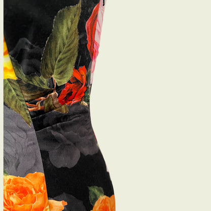 Close-up of a floral pattern with red, orange, and green colors on a black background.