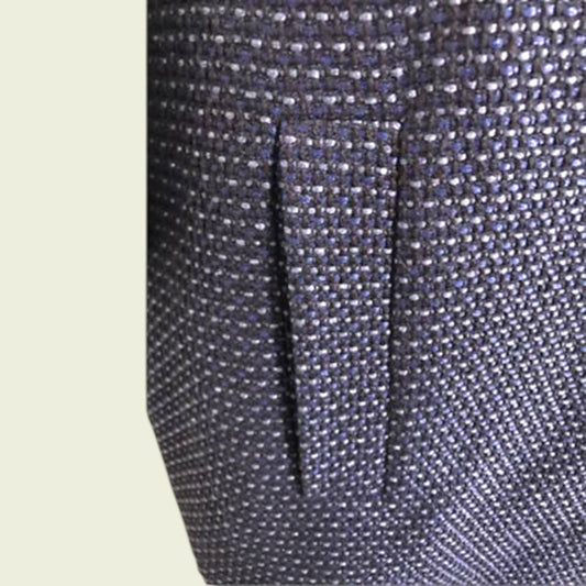 Close-up of a textured fabric with a pocket detail on a light beige background