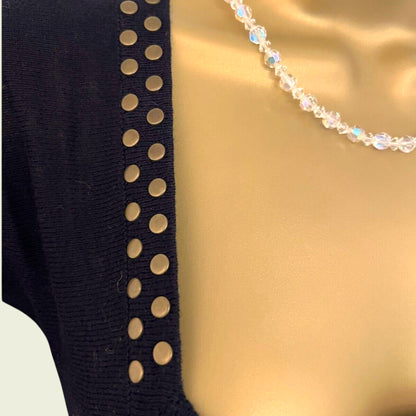 Black garment with gold studs on a beige background
