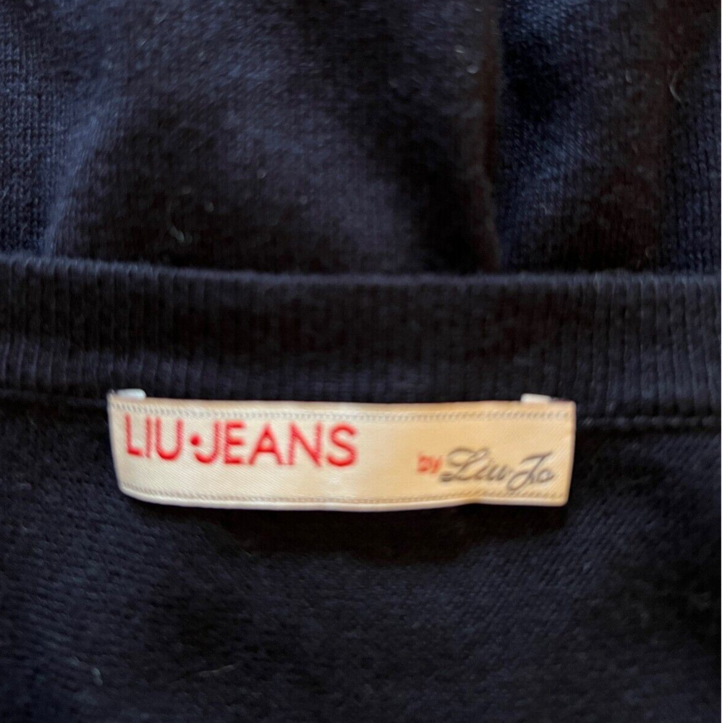 Close-up of a LIU Jeans label on a dark fabric background