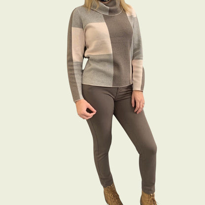 Person wearing a patterned sweater and jeans on a beige background