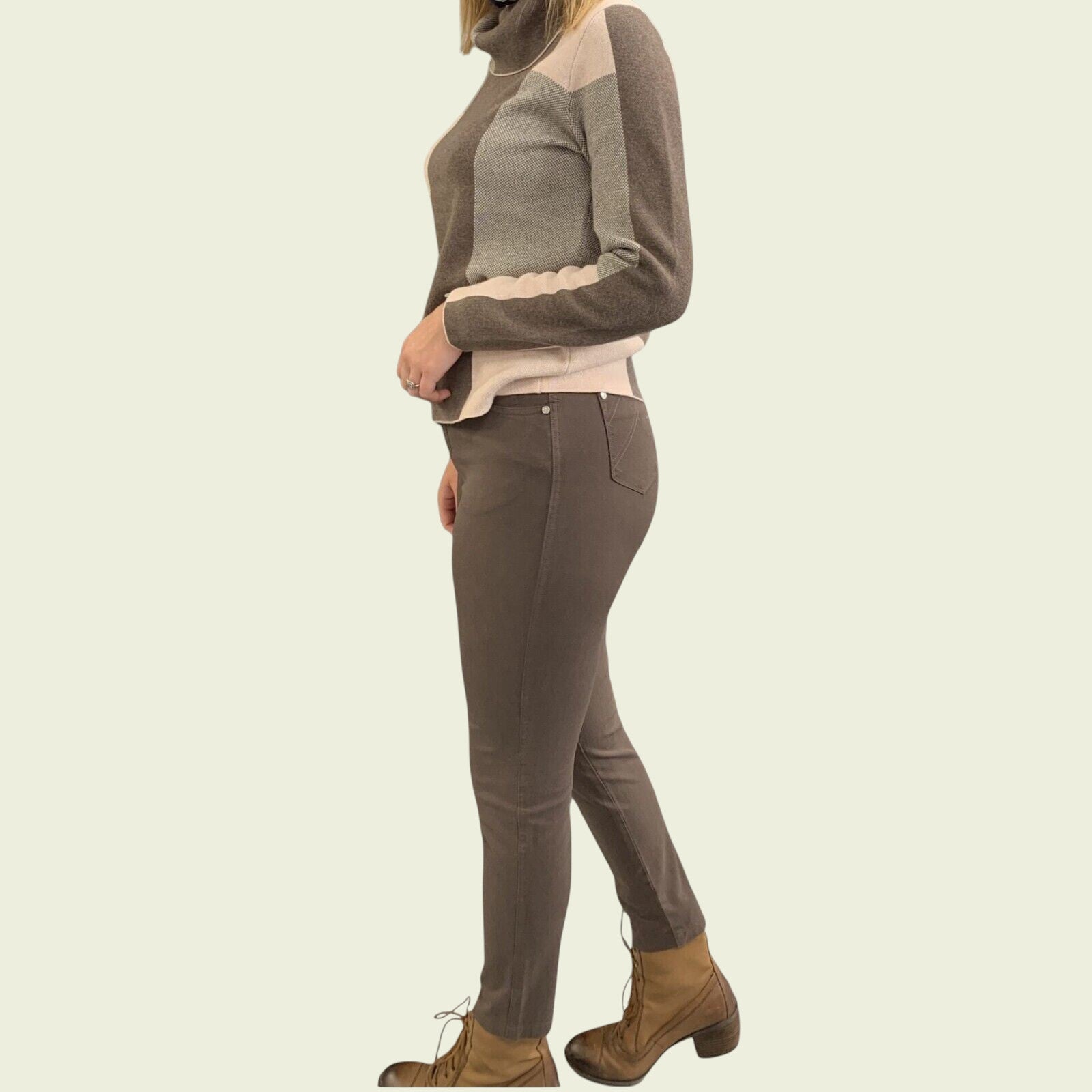 Person wearing a brown sweater and pants with a beige background