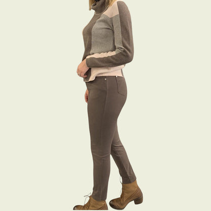 Person wearing a brown sweater and pants with a beige background