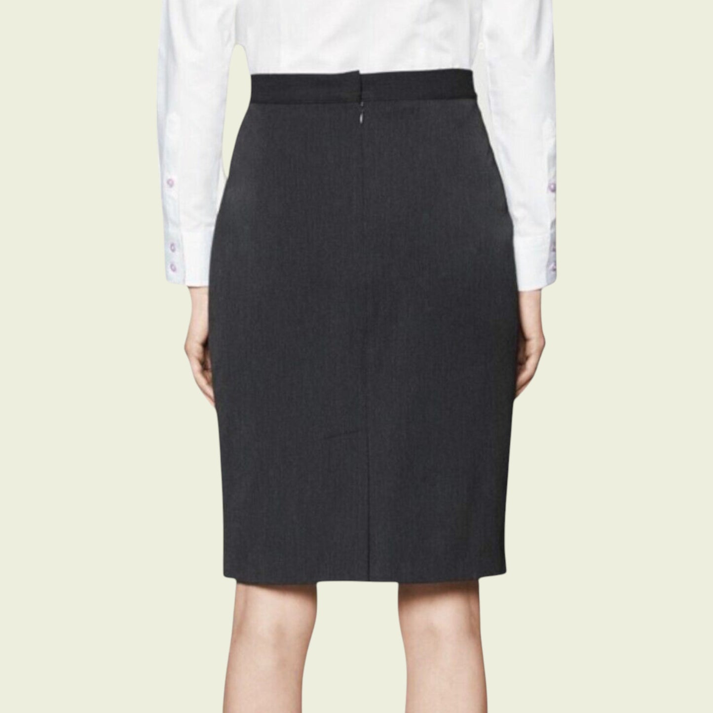 Black pencil skirt worn with a white shirt on a beige background