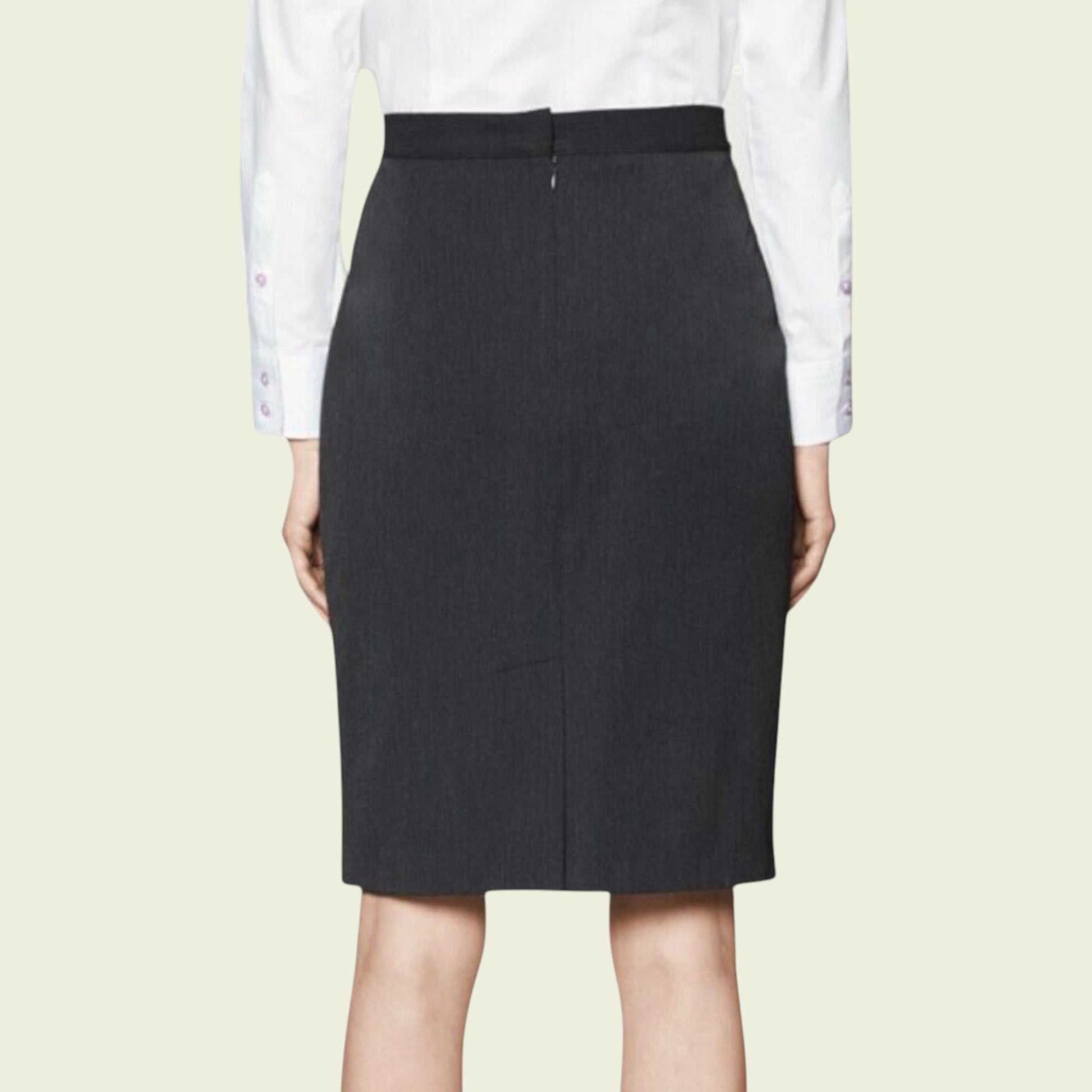 Black pencil skirt worn with a white shirt on a beige background