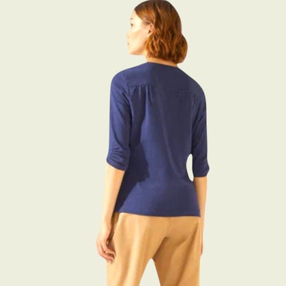 Woman wearing a blue top and beige pants on a light background