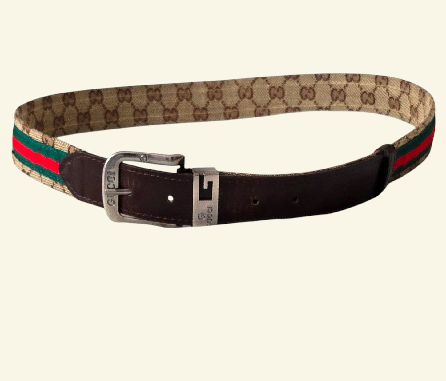 Designer belt with monogram pattern and red and green stripes on a beige background