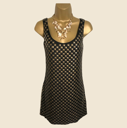 Black and gold patterned dress on a mannequin with a beige background