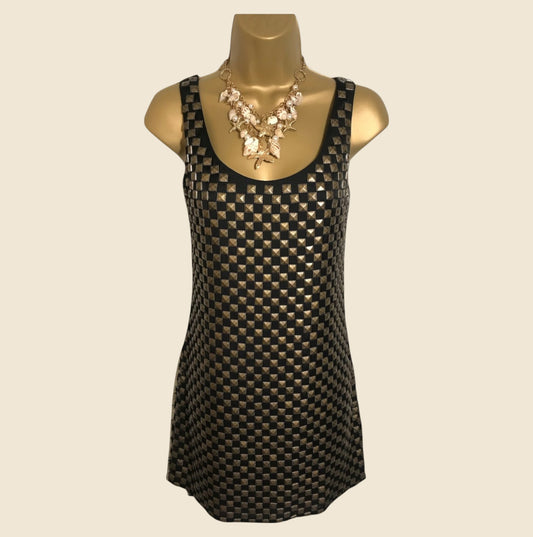 Black and gold patterned dress on a mannequin with a beige background