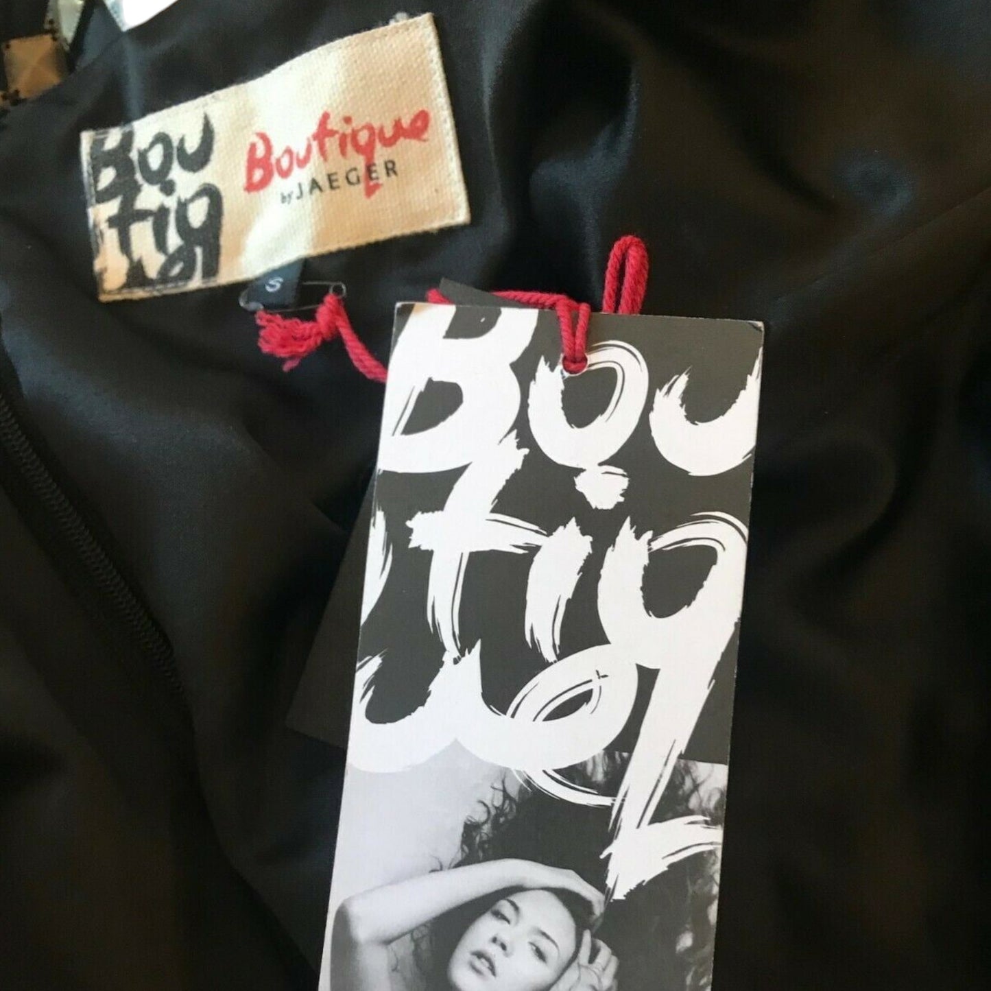 Black garment with 'Boutique by Jaeger' label and tag on a dark background