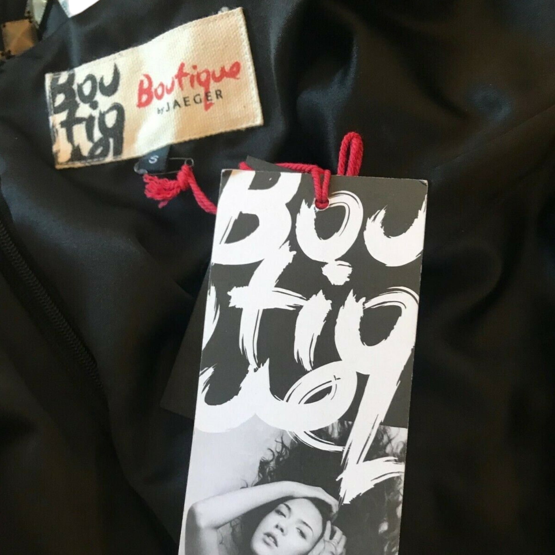 Black garment with 'Boutique by Jaeger' label and tag on a dark background
