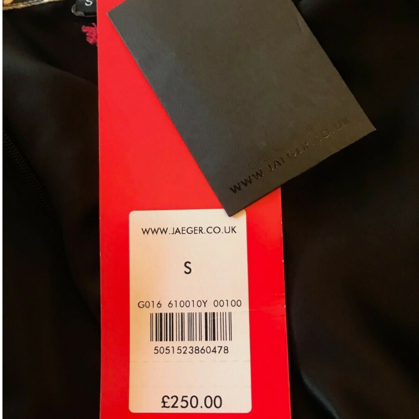 Clothing tag with Jaeger branding and product details on a red background