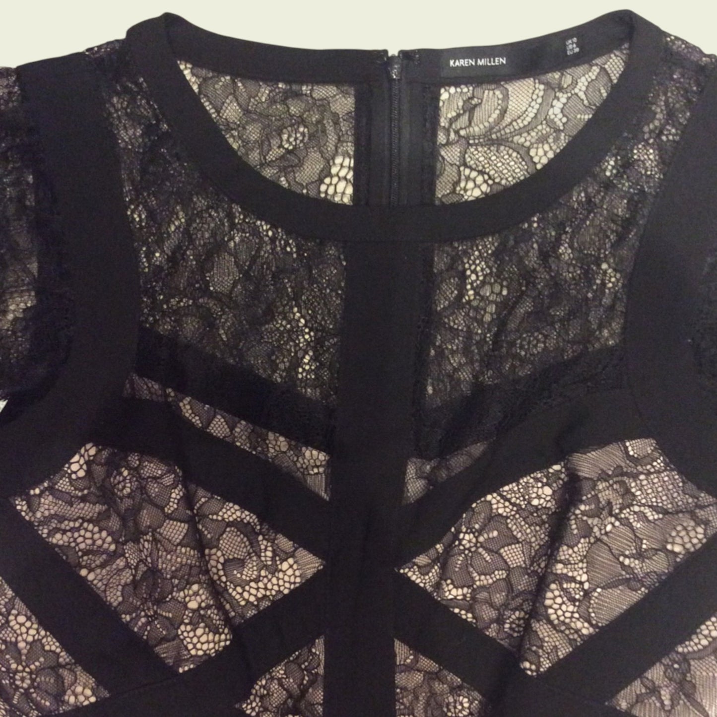 Black lace dress with a zipper detail on a plain background