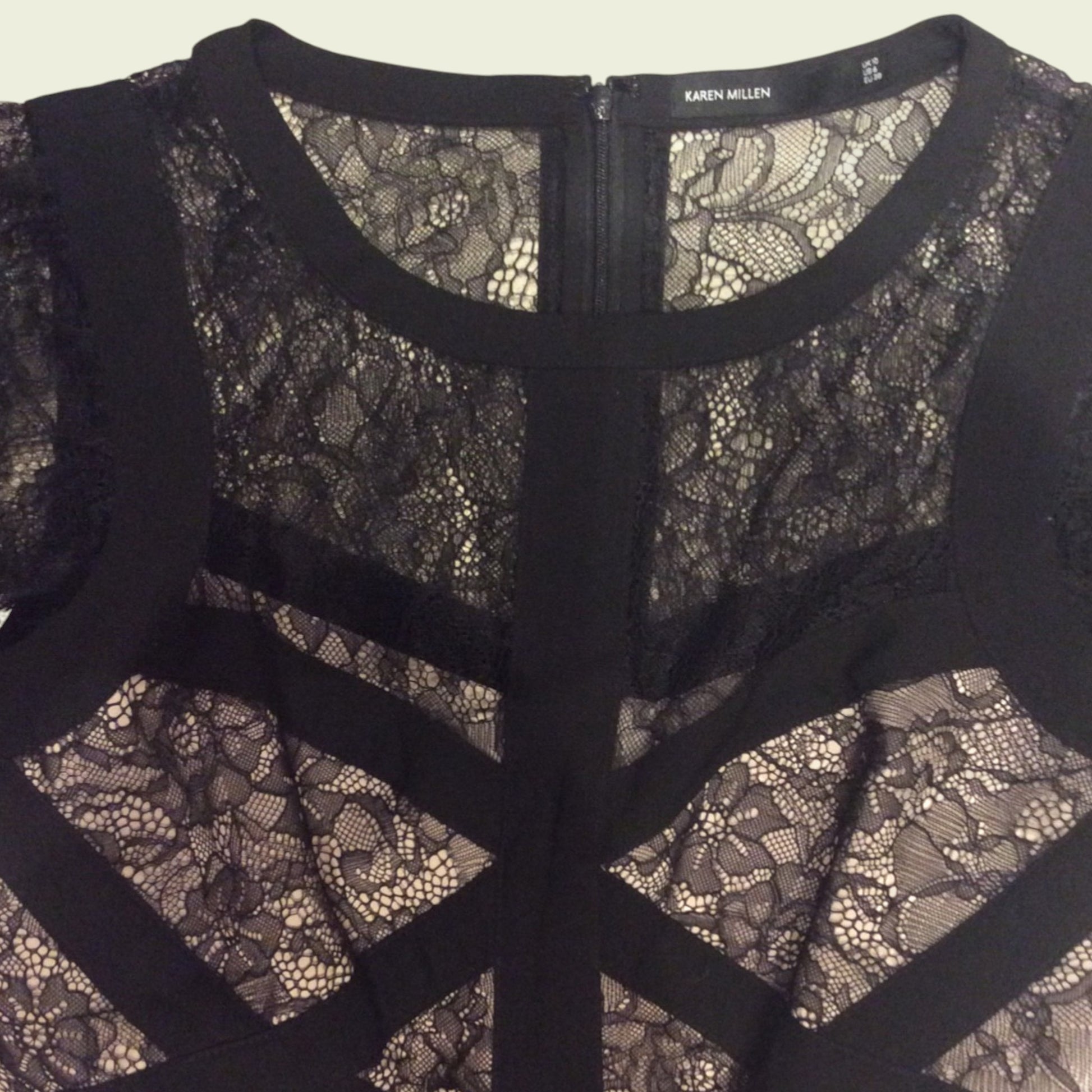 Black lace dress with a zipper detail on a plain background