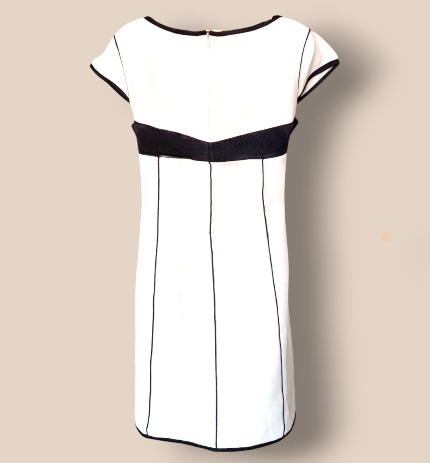 White dress with black accents on a beige background