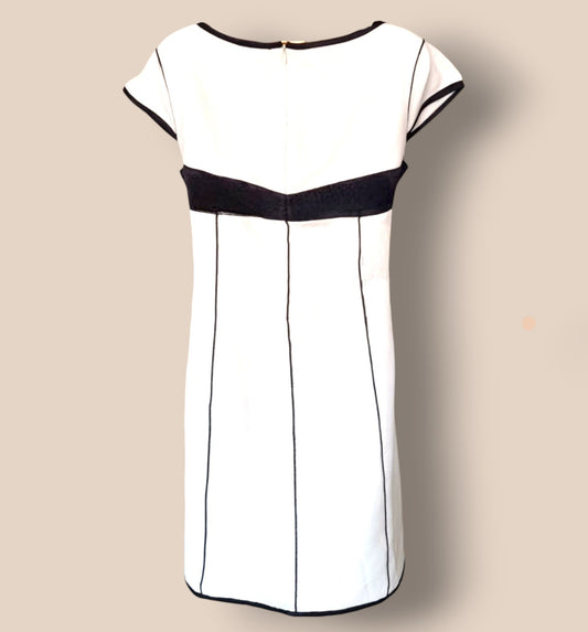 White dress with black accents on a beige background