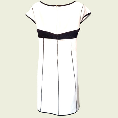 White dress with black accents on a beige background