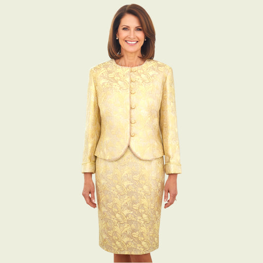 Model wearing gold embroidered dress and jacket on beige background