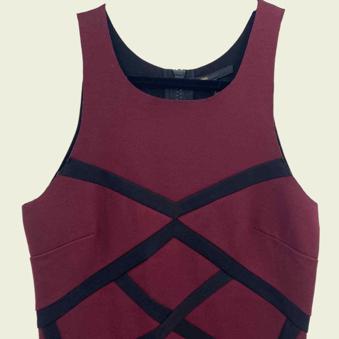 Maroon dress with black criss-cross straps on a beige background