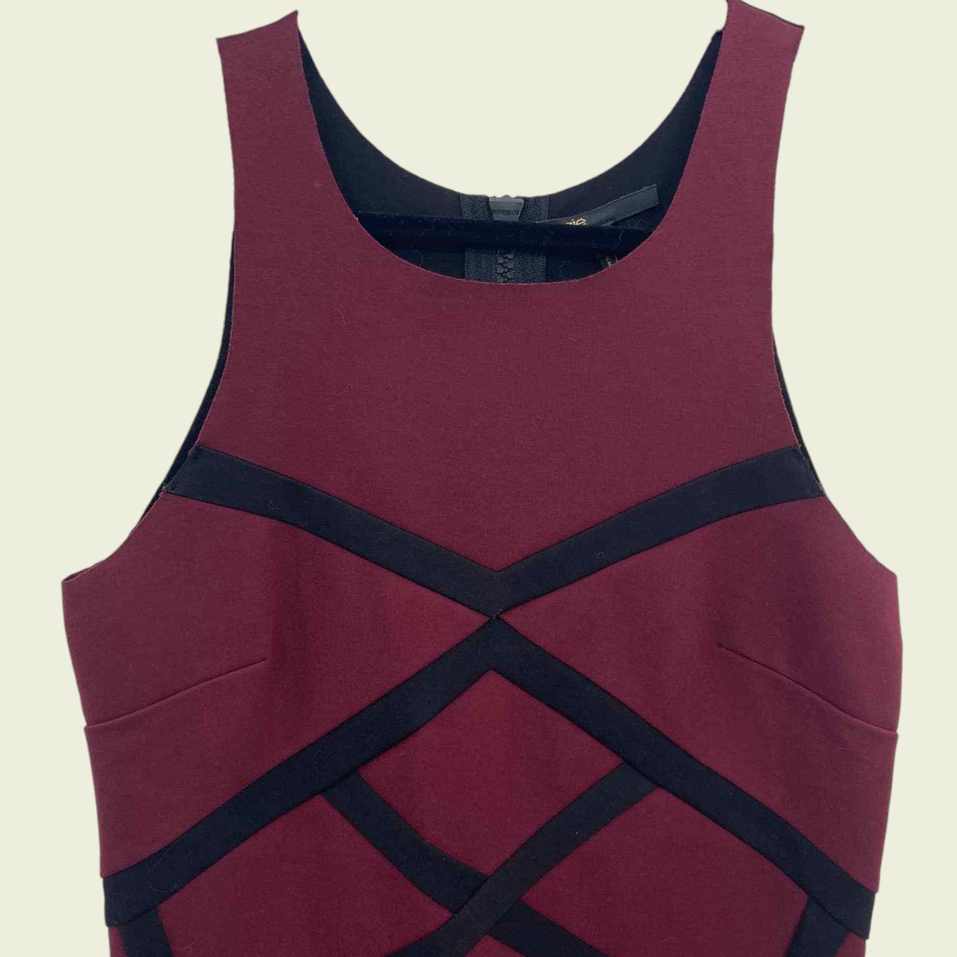 Maroon dress with black criss-cross straps on a beige background