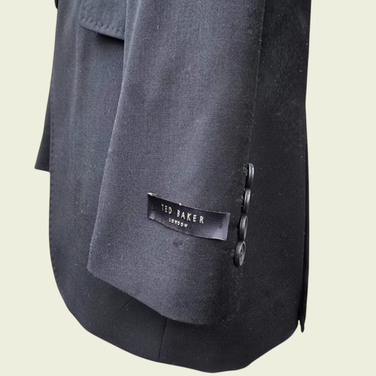 Close-up of a dark blue jacket with a Ted Baker London label on a beige background