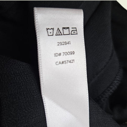 Close-up of a clothing label with care instructions and numbers on a dark fabric background.
