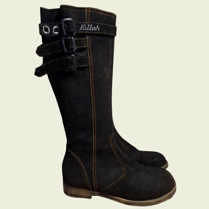 Black knee-high boots with buckles on a beige background