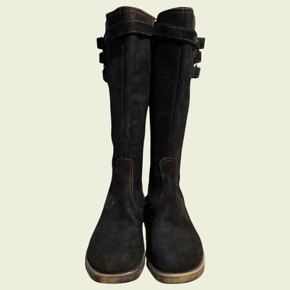 Pair of black boots with buckles on a beige background