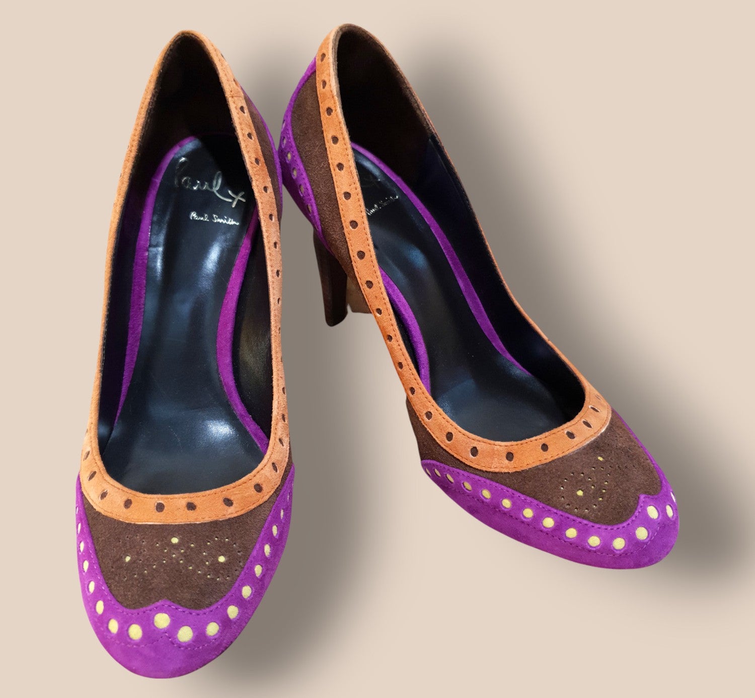 Purple high-heeled shoes with brown accents on a beige background