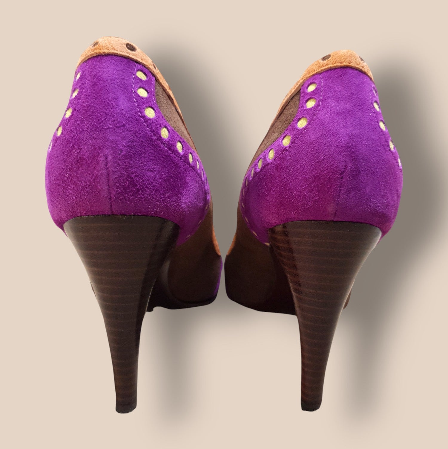 Purple high-heeled shoes with brown soles on a beige background