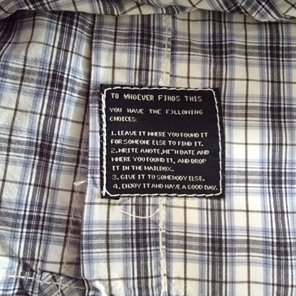 Plaid shirt with a black patch containing text on a checkered fabric background