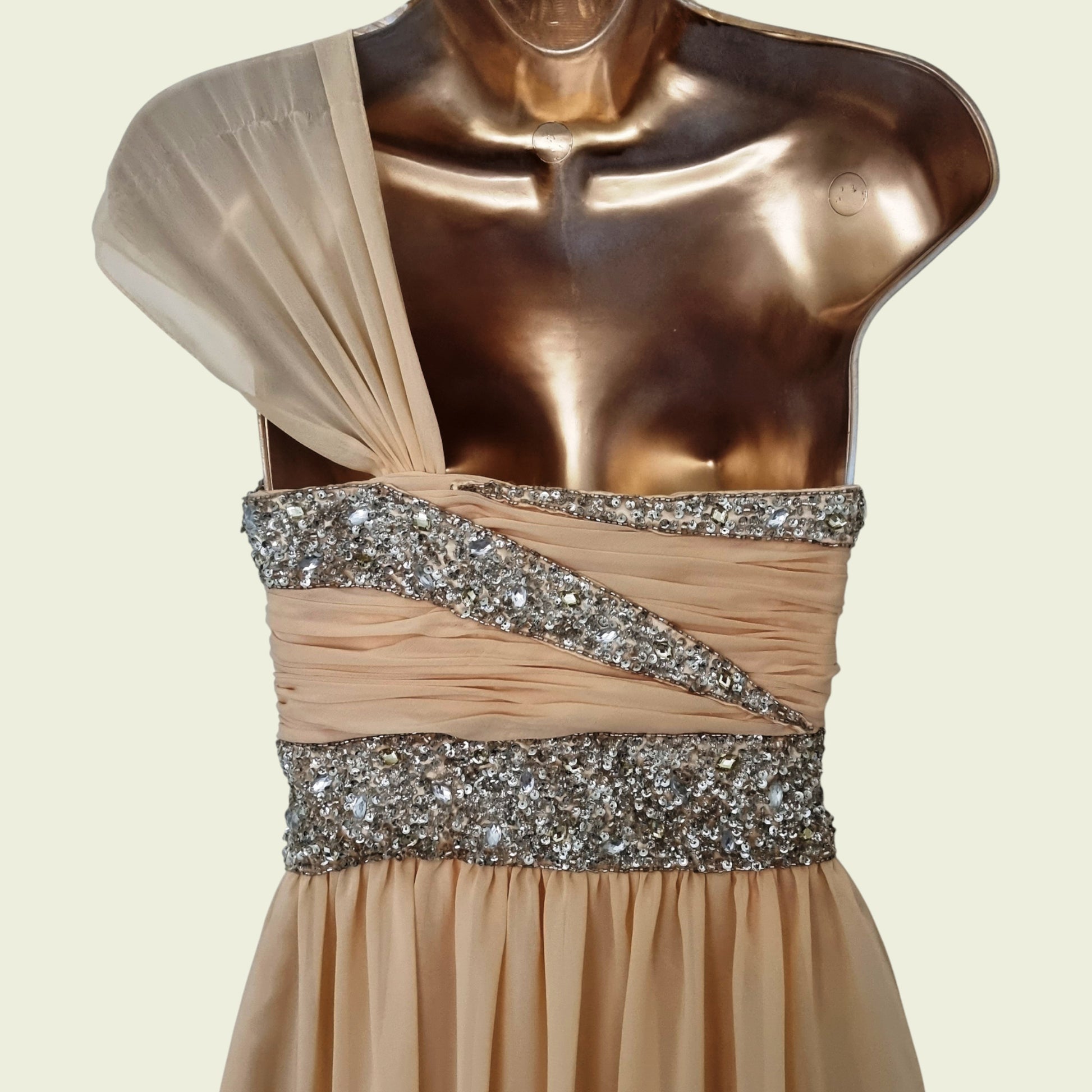 Mannequin wearing a beige evening gown with a silver sequin belt on a beige background
