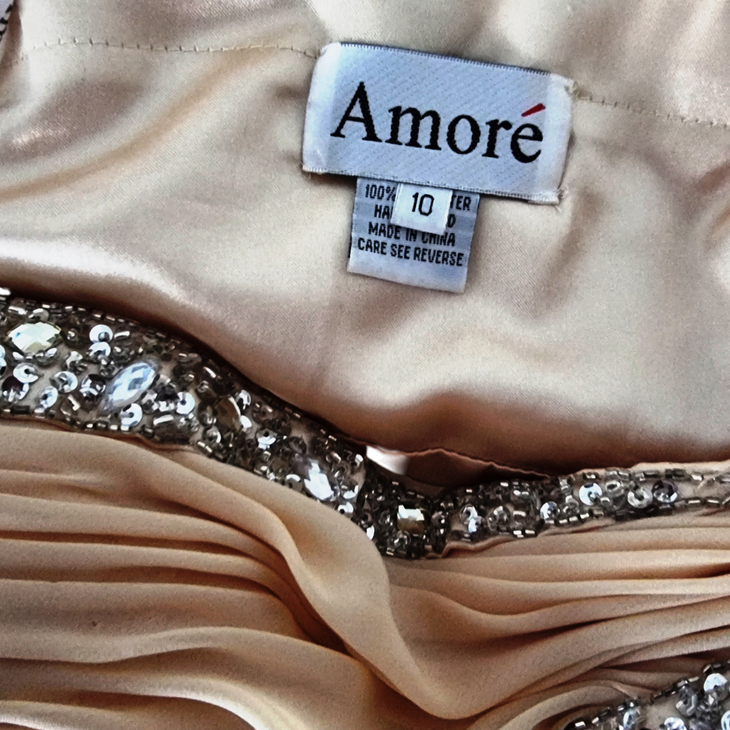 Close-up of a beige fabric with a 'Amore' label and sequin details.